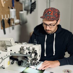 Gründer von Roampacks beim herstellen einer Tasche an einer Nähmaschine.