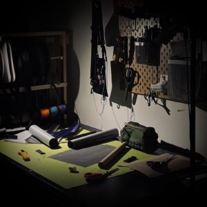 Einblick in die Gemütliche Werkstatt von Roampacks mit Blick auf den Schneidetisch und Stoffrollen in warmem Licht.